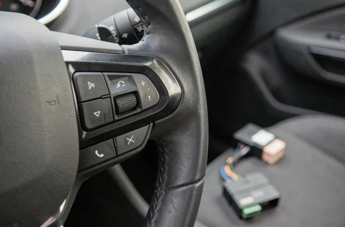 Gros plan sur les boutons multifonctions du volant Peugeot et l'emplacement de l'autoradio double DIN avec adaptateur CANbus
